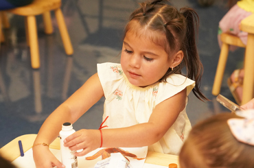 A young girl doing a craft with a glue stick.