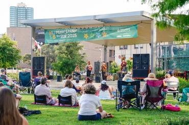 people sitting in lawn chairs watching a live music performance on the Capitol Mall outside the Bullock Museum.