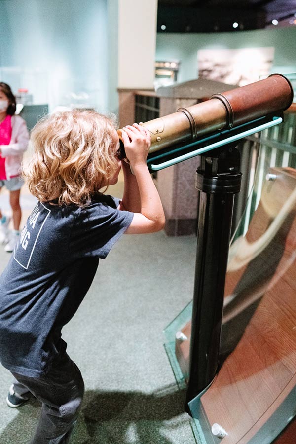 a young boy using an interactive telescope at the Bullock Museum