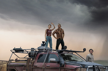 movie poster for "Twisters" with three people standing on top of and around a large truck