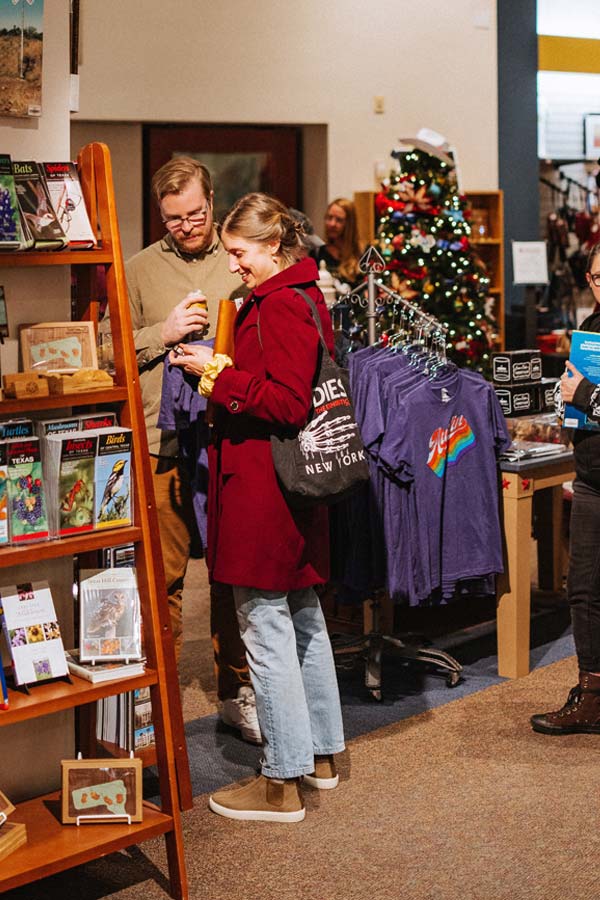 two young adults looking at items for sale near a Christmas tree in the Museum Store