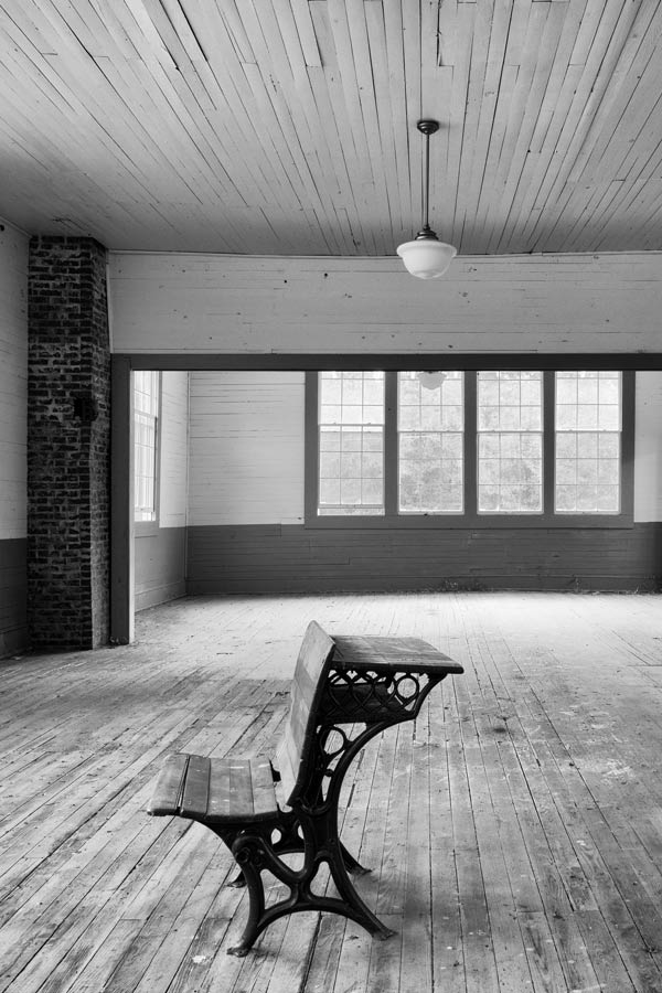 interior black and white photo of an old classroom seat