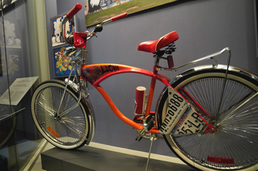 a red bicycle with Chicano imagery painted on it on display at the Bullock Museum