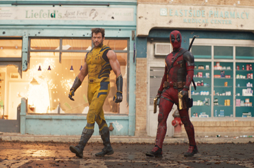 deadpool and wolverine walking down a destructed town street