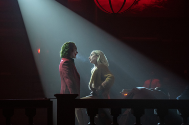 a still image of Joker and Harley performing on a stage under a spotlight