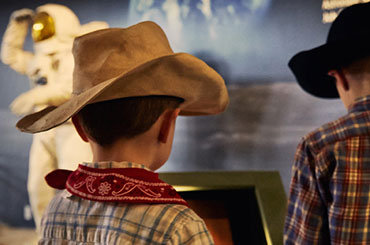 two children wearing cowboy hats and looking at an exhibit at the Bullock Museum