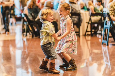 two children dancing and wearing cowboy boots.
