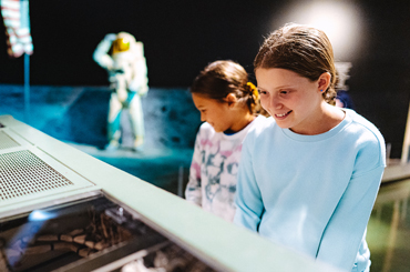 two young girls looking at a space exhibit at the Bullock Museum