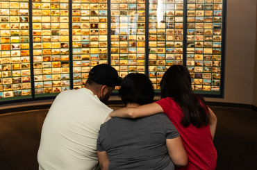 Three people looking at an exhibit with postcards.