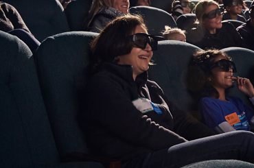 a woman wearing IMAX 3D glasses and watching a movie in the Bullock IMAX Theatre