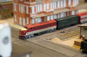 a red and white model train moving through a town